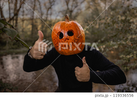 Positive man with pumpkin head for Halloween showing thumbs up, like gesture. Jack-o-lantern costume.Trick or treat. 119336556