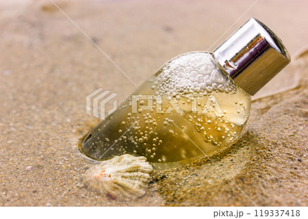 Shower product. Plastic, glass cosmetic bottle with liquid on a sandy coast, beach, shore of a sea, ocean. Natural eco cosmetics for a face body skin care. Container of shower gel shampoo, liquid soap Shower product. Plastic, glass cosmetic bottle with liquid on a sandy coast, beach, shore of a sea, ocean. Natural eco cosmetics for a face body skin care. Container of shower gel shampoo, liquid soap 119337418