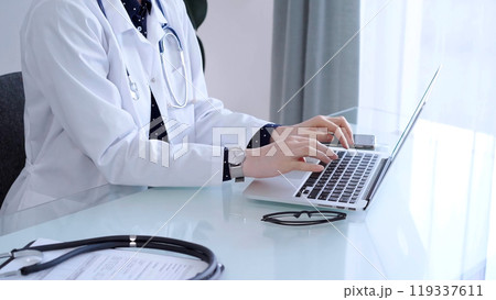 Doctor woman is sitting and typing on laptop computer, hands close up. Medicine and healthcare concept Doctor woman is sitting and typing on laptop computer, hands close up. Medicine and healthcare concept 119337611