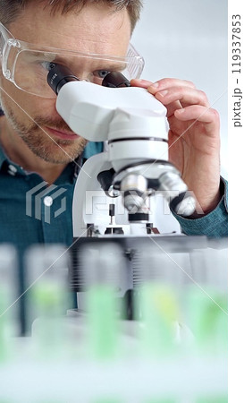 Man scientist with protective glasses using microscope in laboratory. Microbiology science concept 119337853