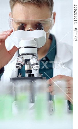 Man scientist with protective glasses using microscope in laboratory. Microbiology science concept 119337997
