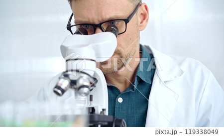 Man scientist with protective glasses using microscope in laboratory. Microbiology science concept 119338049