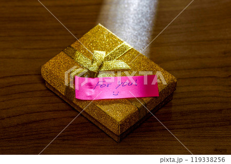 Gift box with a note on a wooden table surface. Gift box with a note on a wooden table surface. 119338256