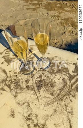 Two glasses of champagne draped with a heart from the sand . High quality photo 119338682