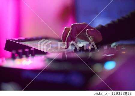 control DJ for mixing music with blurred people dancing at party in nightclub. 119338918