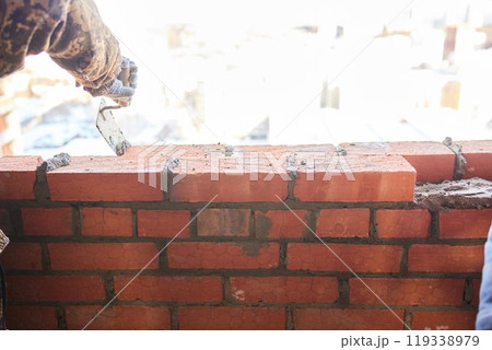 professional construction worker laying bricks and building barbecue in industrial site. Detail of hand adjusting bricks 119338979