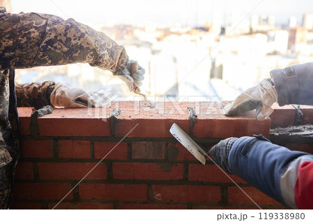 professional construction worker laying bricks and building barbecue in industrial site. Detail of hand adjusting bricks professional construction worker laying bricks and building barbecue in industrial site. Detail of hand adjusting bricks 119338980
