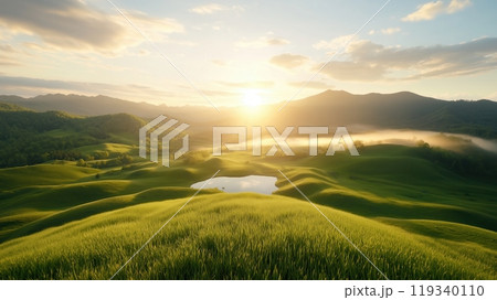 Breathtaking sunrise over lush green hills, with a serene pond reflecting the warm light of the morning sun, creating a peaceful and idyllic natural scene. 119340110
