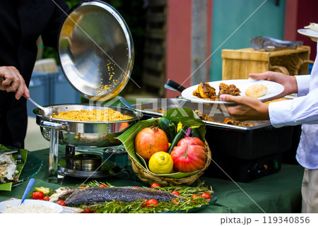 A chef cook puts freshly cooked food on a plate. Stainless steel buffet container, Food tray. Tables set at a banquet. A fruit and vegetable composition. Fresh fruits, vegetables, fish, salat couscous A chef cook puts freshly cooked food on a plate. Stainless steel buffet container, Food tray. Tables set at a banquet. A fruit and vegetable composition. Fresh fruits, vegetables, fish, salat couscous 119340856