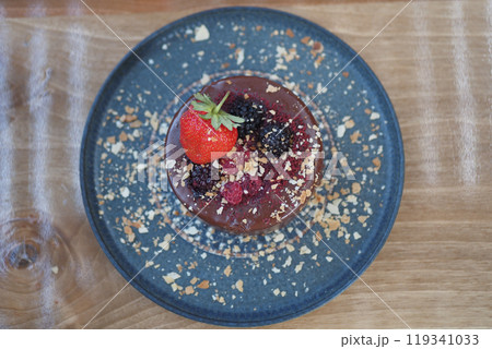 Enjoy a gourmet dessert topped with fresh berries and nuts on a lovely blue plate 119341033