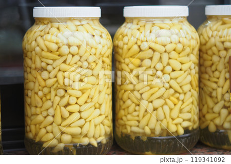 Beautifully arranged jars of vibrant and pickled yellow vegetables displayed attractively 119341092