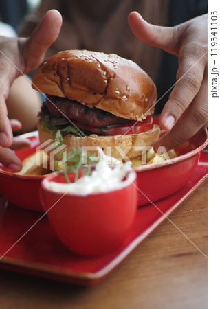 hand holding beef burger on table close up  119341103