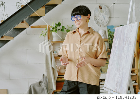 Young adorable drawing teacher standing next to huge canvas while explaining new topic 119341235