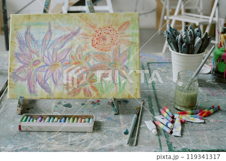 Medium close up of colorful floral painting on canvas with acrylic paint tubes on old dirty table 119341317