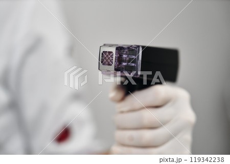 A healthcare worker holds a medical instrument in a sterile environment A healthcare worker holds a medical instrument in a sterile environment 119342238