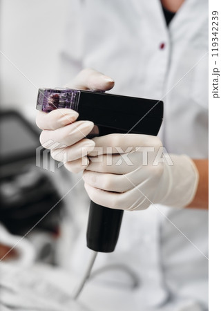Professional uses handheld device for skin treatment in a clinical setting Professional uses handheld device for skin treatment in a clinical setting 119342239