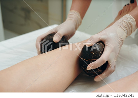 Massage therapist uses volcanic stones for a soothing treatment on legs Massage therapist uses volcanic stones for a soothing treatment on legs 119342243