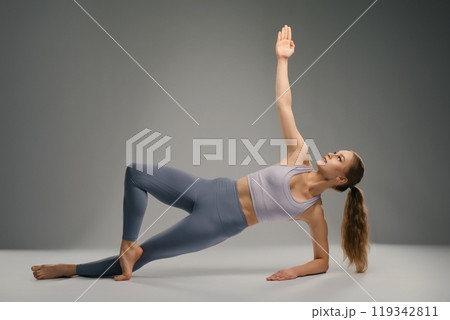 Woman performing side plank exercise in studio during fitness session Woman performing side plank exercise in studio during fitness session 119342811