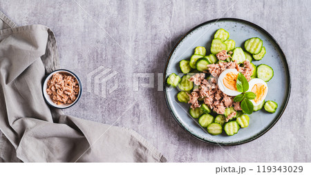 Keto salad with tuna, cucumber, egg and basil in a bowl on the table top view web banner 119343029