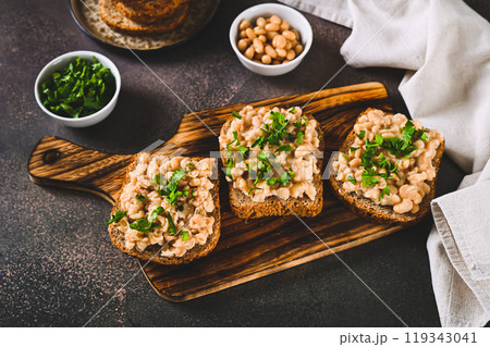 Bruschetta with mashed white beans and parsley on rye bread on a board Bruschetta with mashed white beans and parsley on rye bread on a board 119343041