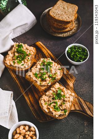 Bruschetta with mashed white beans and parsley on rye bread on a board vertical view 119343043