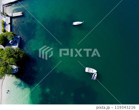 A clear azure lagoon with beaches and several private boats at anchor 119343216