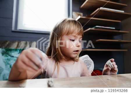 Girl engaged in creative clay modeling indoors at a cozy workspace 119343266