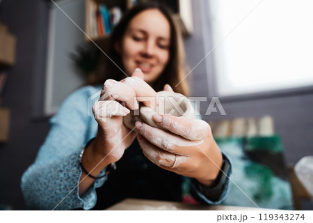 A woman crafting pottery in a cozy studio during the afternoon 119343274