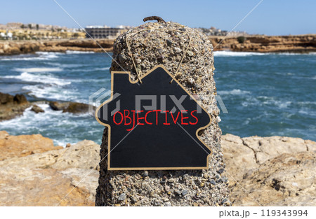 Objectives symbol. Concept word Objectives on beautiful chalk blackboard. Beautiful red stone and blue sky sea background. Business objectives concept. Copy space. 119343994