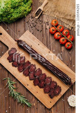 Smoked salami sticks on a wooden board with herbs, perfect for charcuterie boards and gourmet snacks 119344265