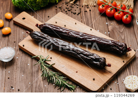 Smoked salami sticks on a wooden board with herbs, perfect for charcuterie boards and gourmet snacks Smoked salami sticks on a wooden board with herbs, perfect for charcuterie boards and gourmet snacks 119344269