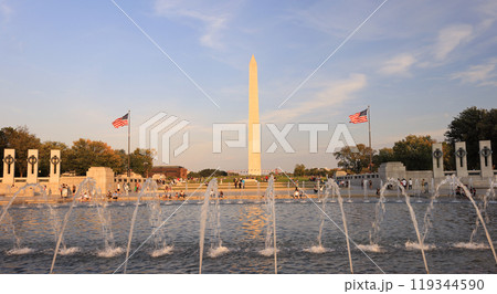 People enjoying the basin and fountains of The World War II Memorial. The Washington Monument is on the background. 119344590