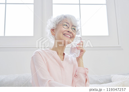 リビングルームでペットボトルを持つシニア女性 119347257