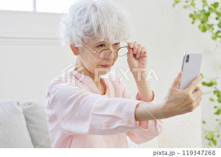 スマートフォンを見る老眼のシニア女性 スマートフォンを見る老眼のシニア女性 119347268