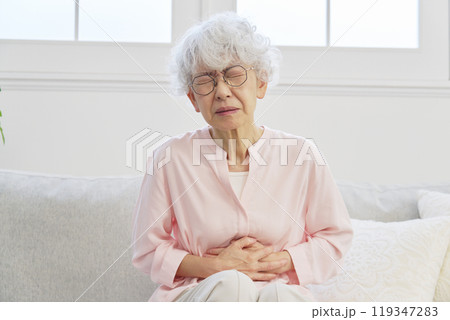 腹痛のシニア女性 リビングルーム 腹痛のシニア女性 リビングルーム 119347283
