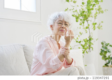 手が痺れるシニア女性　リビングルーム 119347291