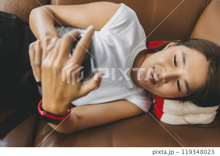 Happy woman lie on the sofa and looking at the social media in the phone. Happy woman lie on the sofa and looking at the social media in the phone. 119348023