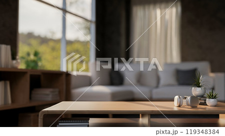 A close-up of a wooden coffee table in a comfortable contemporary living room. 119348384