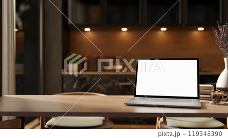 A close-up of a laptop mockup on a hardwood dining table in a contemporary, luxurious kitchen. A close-up of a laptop mockup on a hardwood dining table in a contemporary, luxurious kitchen. 119348390