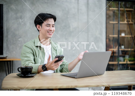 A man is working remotely from a coffee shop, participating in an online meeting via his laptop. A man is working remotely from a coffee shop, participating in an online meeting via his laptop. 119348670