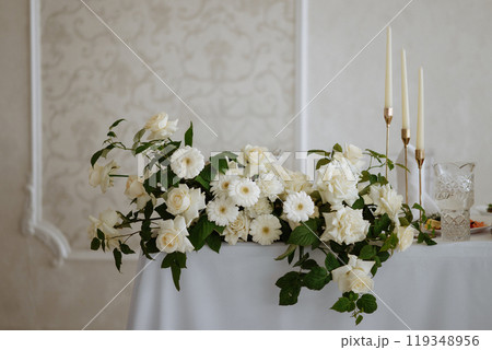 A table with a white tablecloth and a vase of white flowers A table with a white tablecloth and a vase of white flowers 119348956