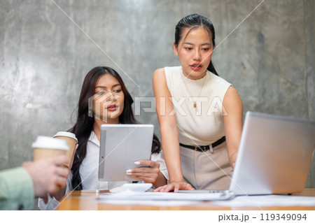 Two attractive Asian businesswomen are focused on reviewing a project on a laptop during a meeting. Two attractive Asian businesswomen are focused on reviewing a project on a laptop during a meeting. 119349094