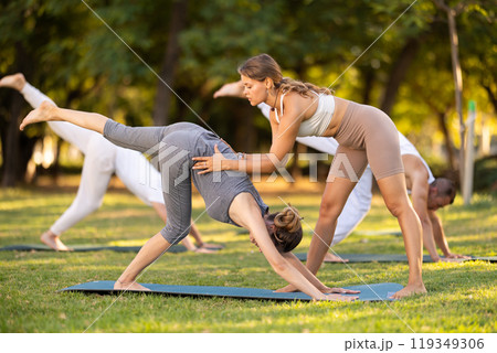 Coach corrects downward facing dog position, helps to perform exercise correctly. 119349306