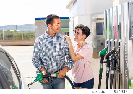 Positive couple filling up tank of their car with gasoline in gas station 119349373