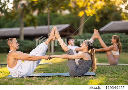 Guy and girl practice pair yoga doing Buddy boat pose asana 119349425