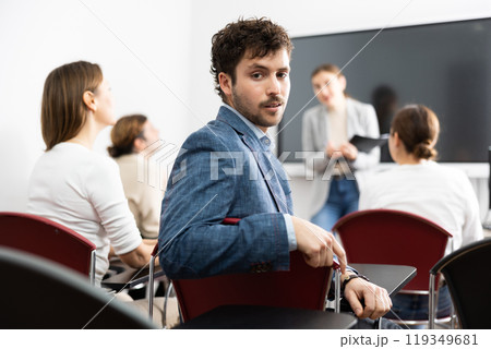 Portrait of successful young man participating in language courses with group of people in classroom Portrait of successful young man participating in language courses with group of people in classroom 119349681