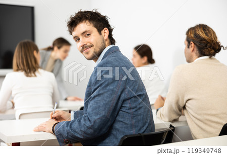 Positive young man turning around and looking at camera during advanced training course in auditory 119349748