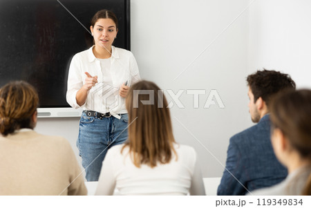 Young female tutor teaching students in college classroom Young female tutor teaching students in college classroom 119349834