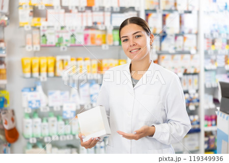 Young female pharmacist posing with remedy in pharmacy Young female pharmacist posing with remedy in pharmacy 119349936