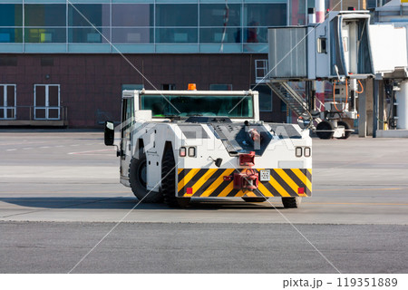Airplane tow tractor near passenger boarding bridge 119351889
